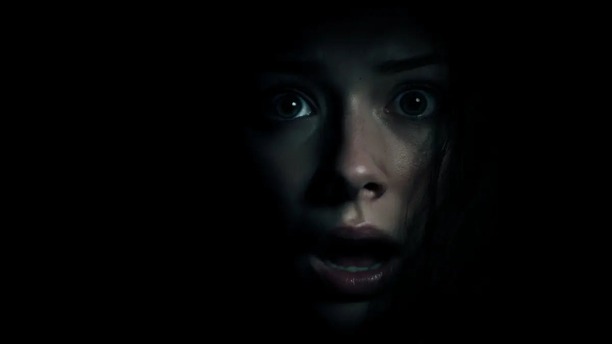 Person with wide eyes in a dark setting