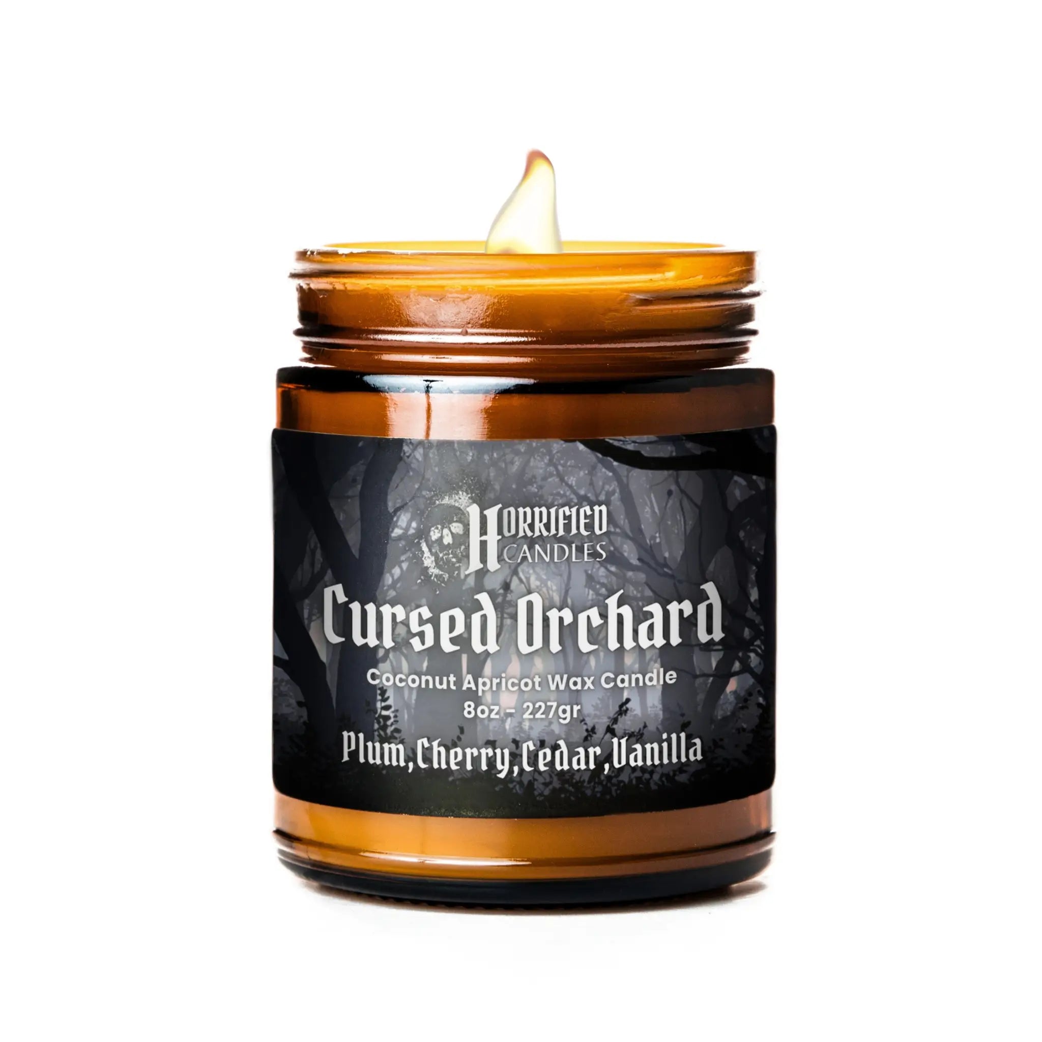 Candle in a glass jar labeled 'Cursed Orchard' by Horrified Candles on a white background.