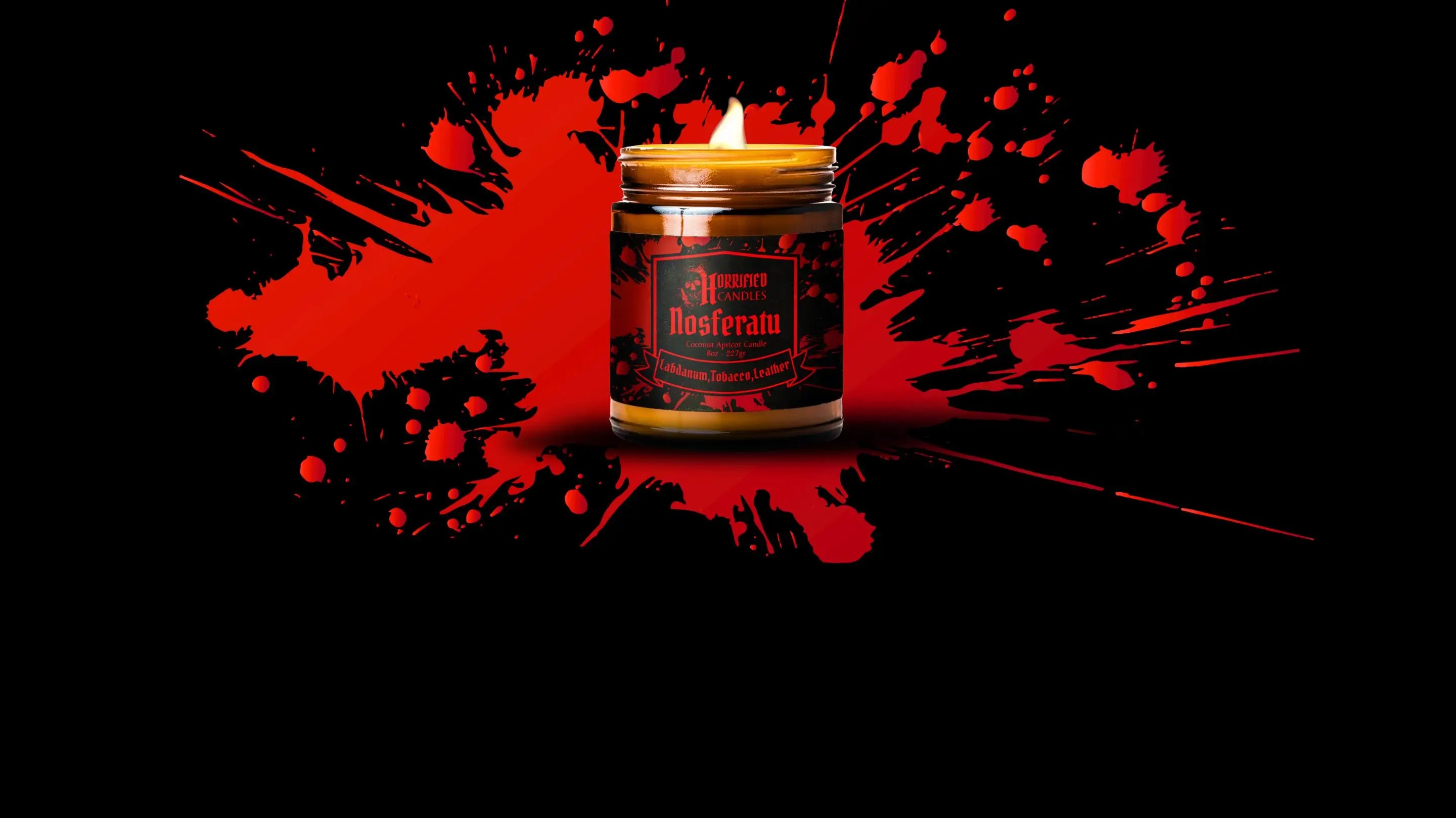 Candle in a decorative container with a red and black design on a dark background