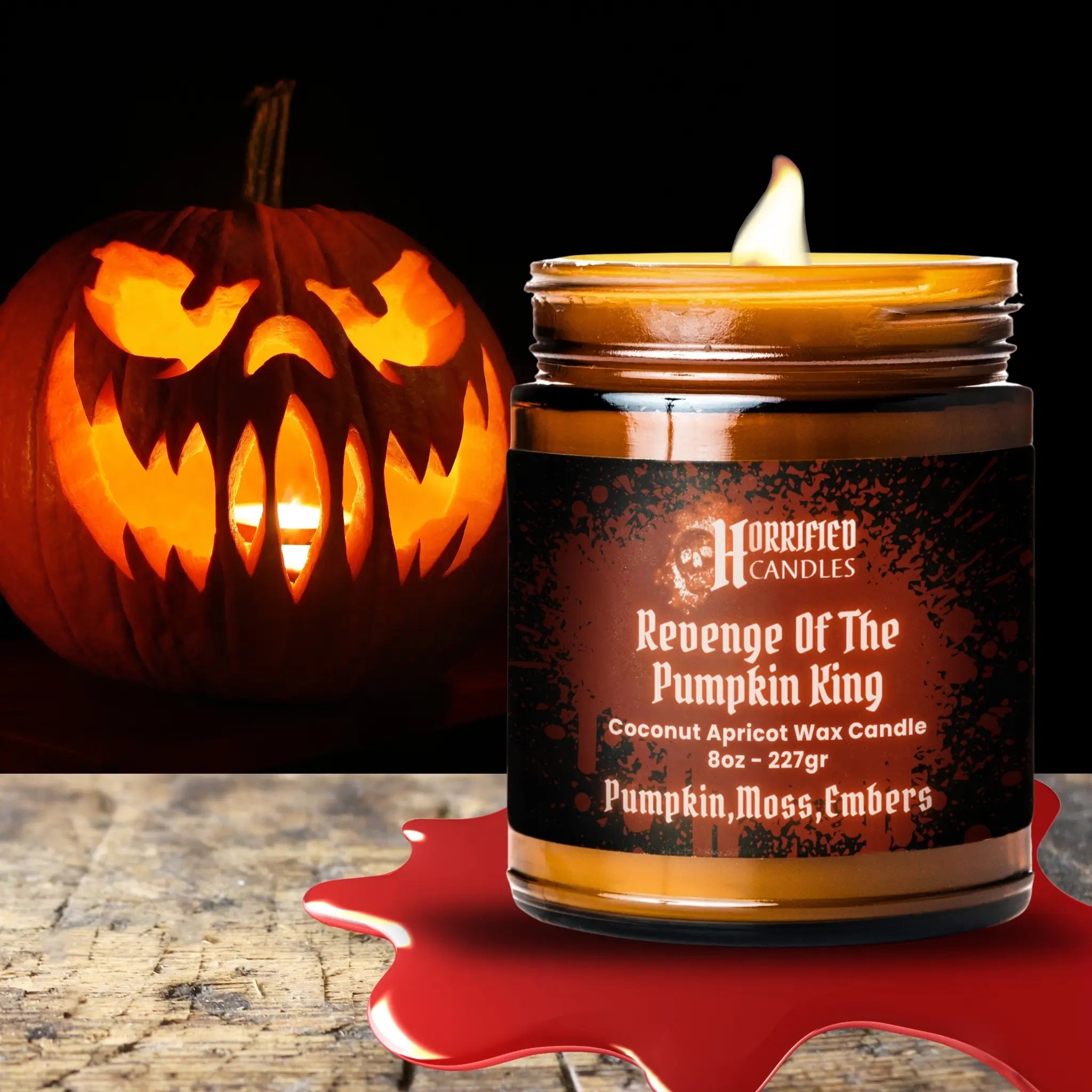 Halloween-themed candle labeled 'Revenge Of The Pumpkin King' next to a carved pumpkin on a dark background.